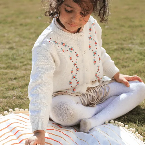 A smiling girl sitting cross-legged on the Circle of Life play mat
