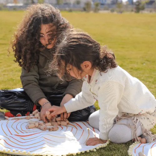A mother and her daughter placing Circle of Life characters on the play mat outdoors