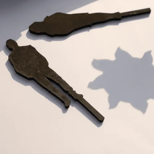 Black wooden Khayal shapes casting shadows on a white surface