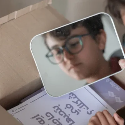 A boy's reflection in the Think Inside the Box mirror above the game cards