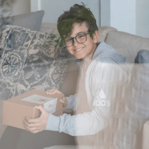 A smiling boy on a sofa opening the Think Inside the Box game