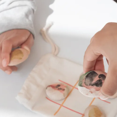 Painted stones placed on the tic-tac-toe grid printed on the Watermelon & Cheese bag